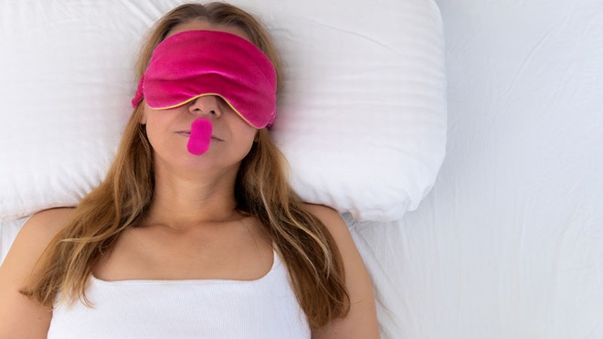 Mulher a dormir com venda nos olhos e mouth taping, uma fita adesiva que tapa a boca