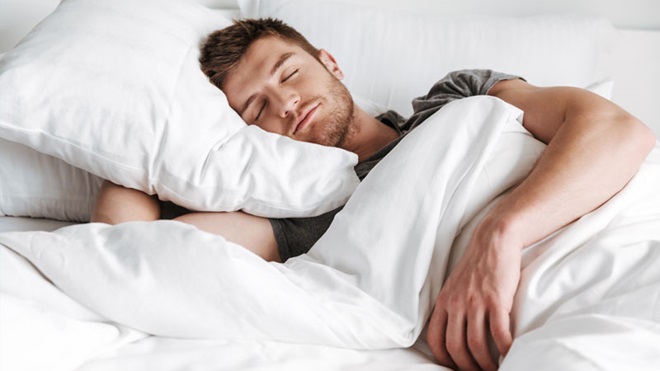 Homem dorme descansado numa cama confortável - alusão ao uso de sobrecolchões