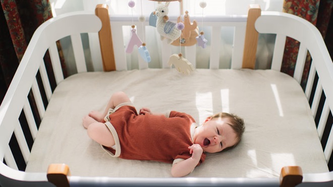 Bebé a dormir numa cama de grades
