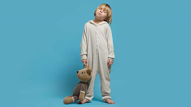 Criança a dormir em pé com ursinho na mão