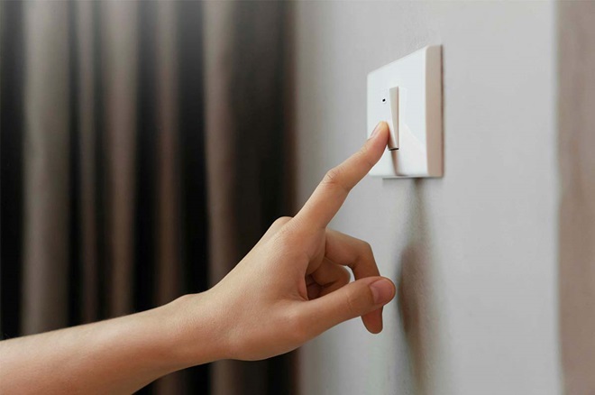 Pessoa a carregar em interruptor elétrico