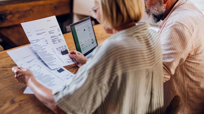Homem e mulher a analisarem as faturas de energia à mesa com computador portátil