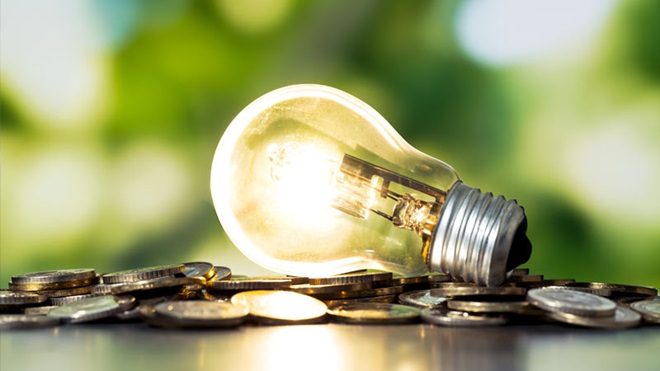 Lâmpada acesa em cima de uma pilha de moedas