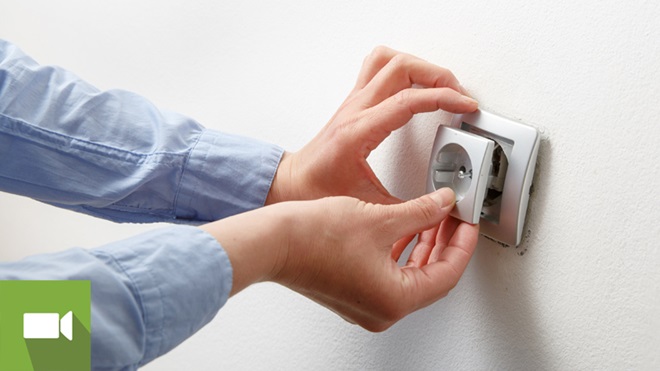 Mãos a reparar tomada solta da parede