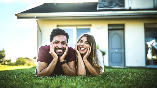 casal deitado na relva em frente a casa
