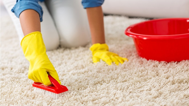 Mulher com luvas amarelas a lavar carpete com produtos de limpeza de carpetes e tapetes