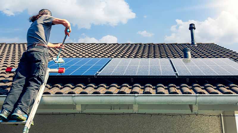 Homem a instalar painel solar em telhado de casa