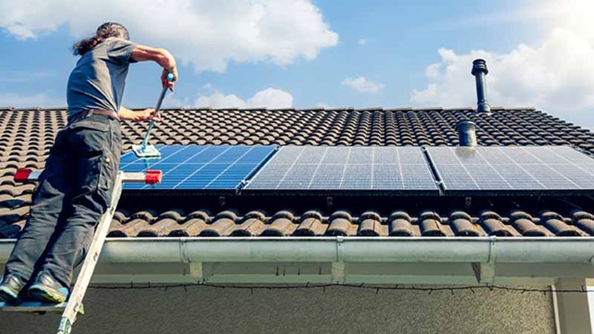 Homem a instalar painel solar em telhado de casa