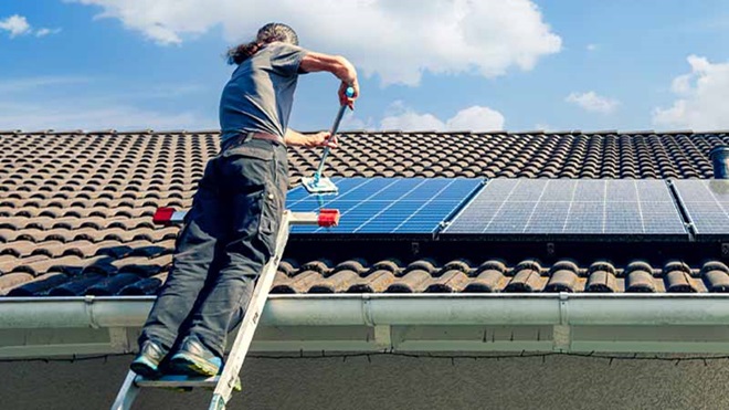 Homem a instalar painel solar em telhado de casa