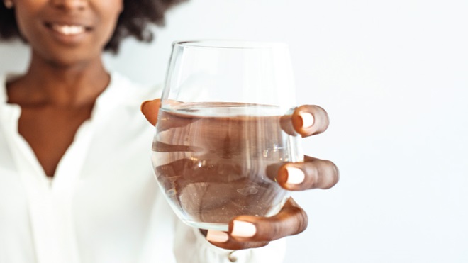 mulher segura um copo de vidro com água