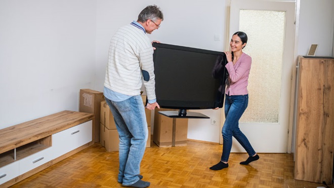 Mulher rodeada por caixas de mudanças, a comparar tarifários de TV, net e voz para a nova casa