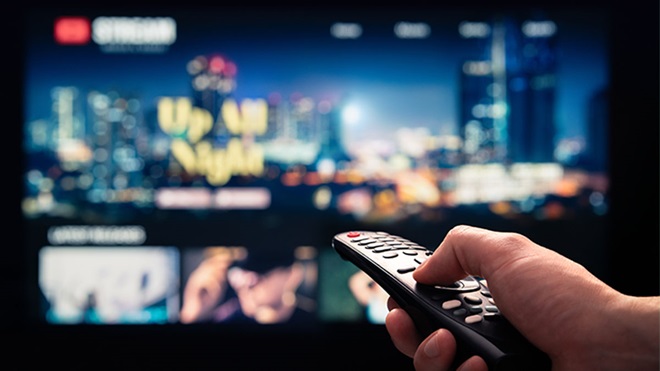 Pessoa a apontar o telecomando para à televisão