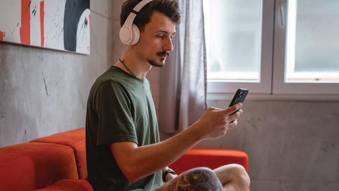 homem sentado no sofá de auriculares