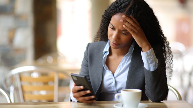 Mulher a consultar telemóvel com ar preocupado