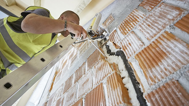 construtor a reforçar paredes de uma casa com materiais de isolamento térmico 