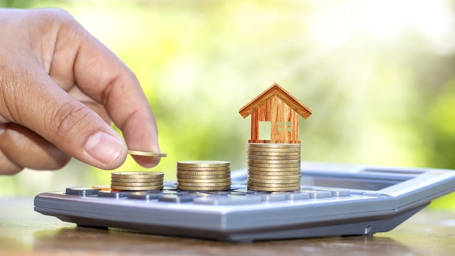 Mão a colocar moedas em cima de calculadora