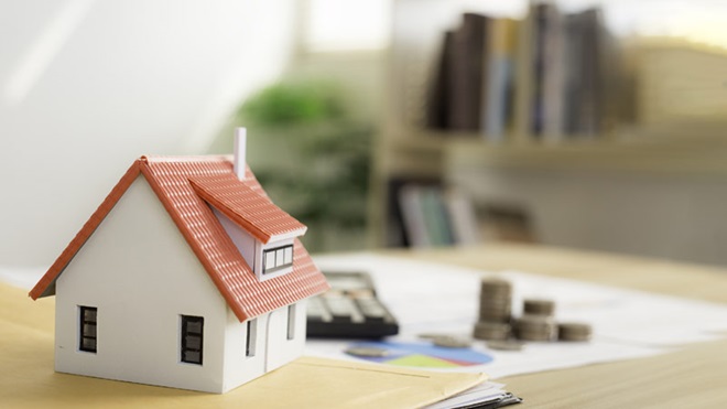 miniatura de uma casa em cima de uma mesa com dinheiro e calculadora