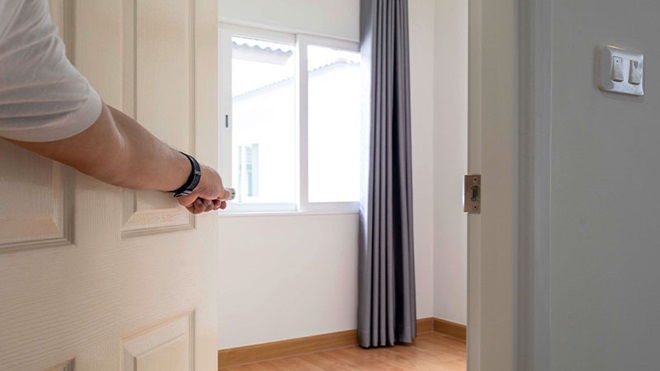 pessoa a abrir porta para quarto vazio