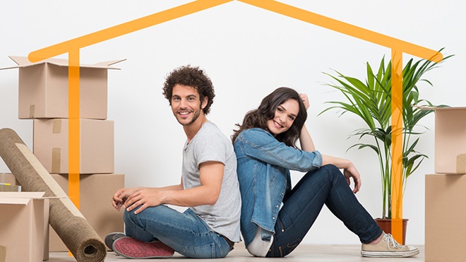 casal jovem sentado no chão da nova casa com caixotes ao lado