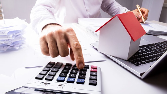 homem a utilizar calculadora para fazer contas das despesas para incluir no IRS