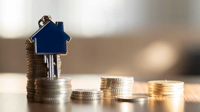 Montinhos de moedas com chave de casa pendurada no maior