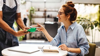 Mulher europeia a pagar com o telemóvel - alusão a euro digital