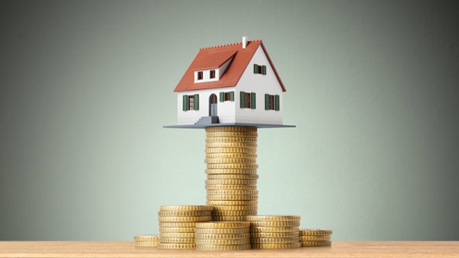 Casa assente em pilhas de moedas, uma delas muito elevada