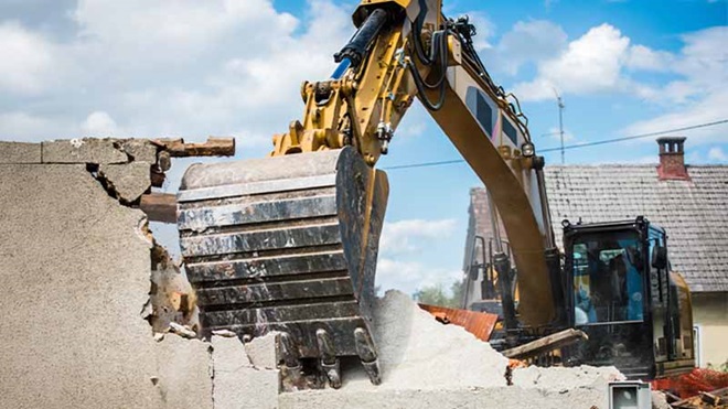 retroescavadora a demolir edifício num belo dia de céu pouco nublado