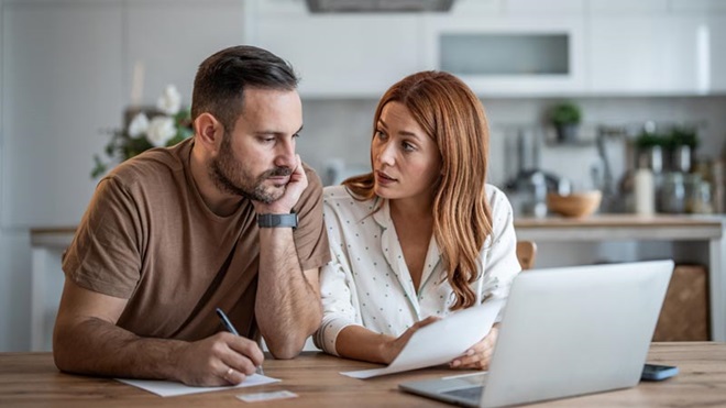 Casal com ar preocupado em frente a um computador