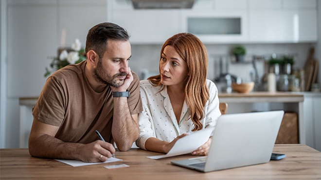 casal a consultar informação em portátil na mesa da cozinha