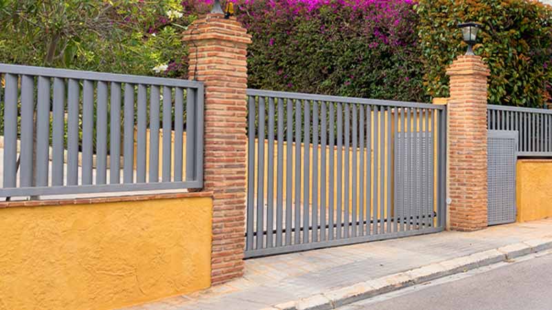 Muro amarelo e portão cinzento de casa privada, fechado