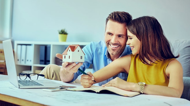 casal em frente a um computador portáteil, a fazer contas para baixar a prestação do crédito à habitação da casa.