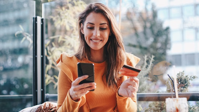 senhora com telemóvel e cartão na mão