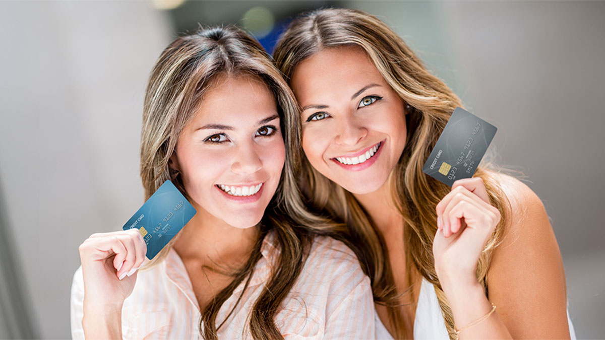 Duas mulheres satisfeitas com os seus cartões do melhor banco para abrir conta jovem
