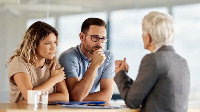 Casal com ar sério reclama com um funcionário do banco para resolver conflito