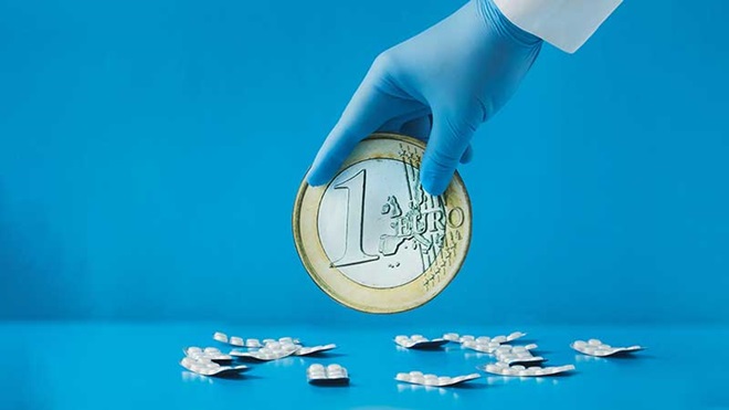 Mão com luva hospitalar a segurar uma moeda de euro