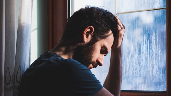 homem triste, de luto, à janela