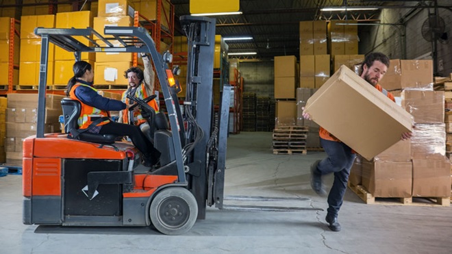 máquina empilhadora com trabalhadores a conversar num armazém