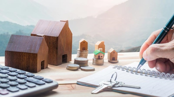 casas, moedas, calculadora e pessoa a escrever numa agenda