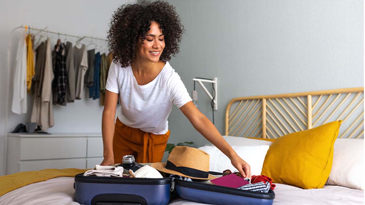 Mulher jovem ativa no quarto, em casa, faz a mala para um destino de férias