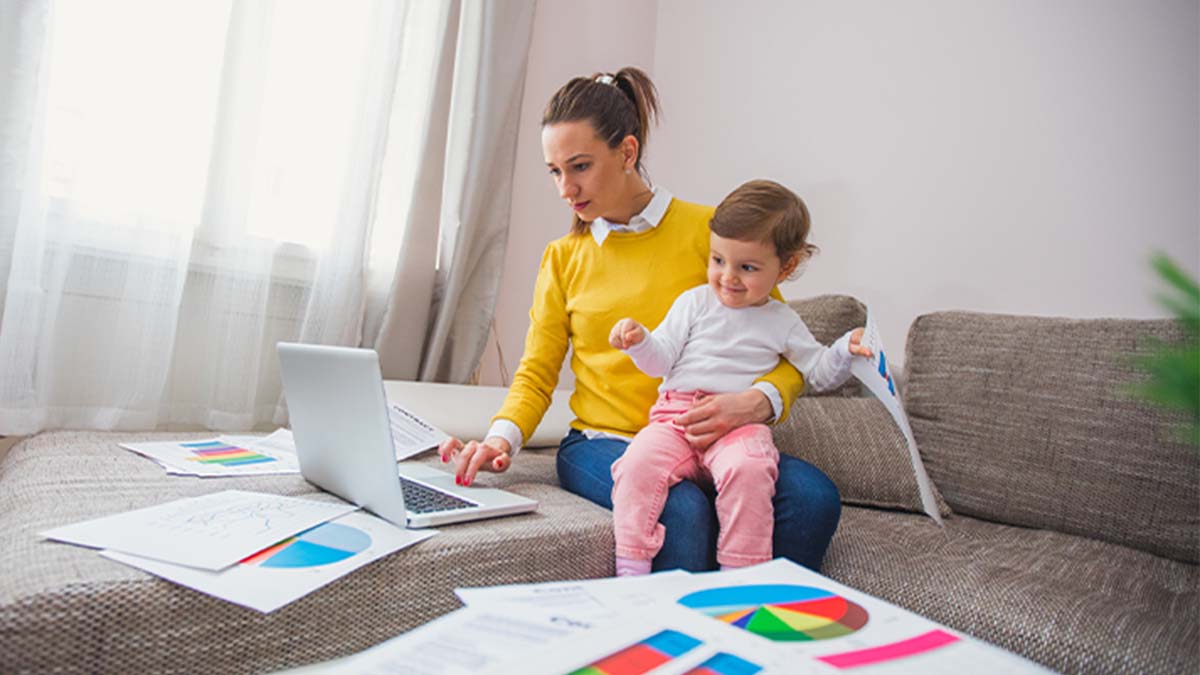 mãe com filho bebé ao colo a trabalhar ao computador