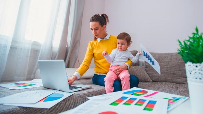 mãe a trabalhar em casa, enquanto a criança está ao seu lado