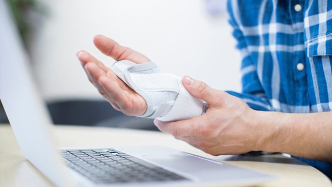 senhor ao computador com uma lesão na mão