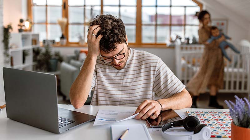 Rapaz preocupado a ler uma carta junto ao computador