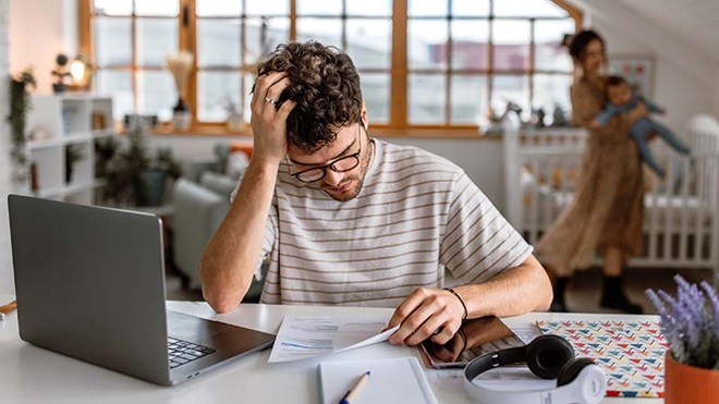 Rapaz preocupado a ler uma carta junto ao computador