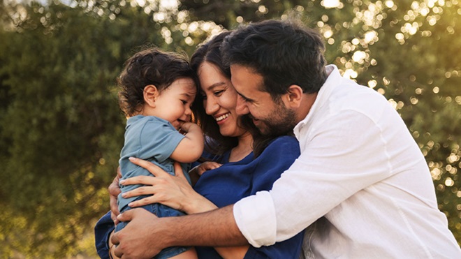 Casal sorridente com criança ao colo no exterior