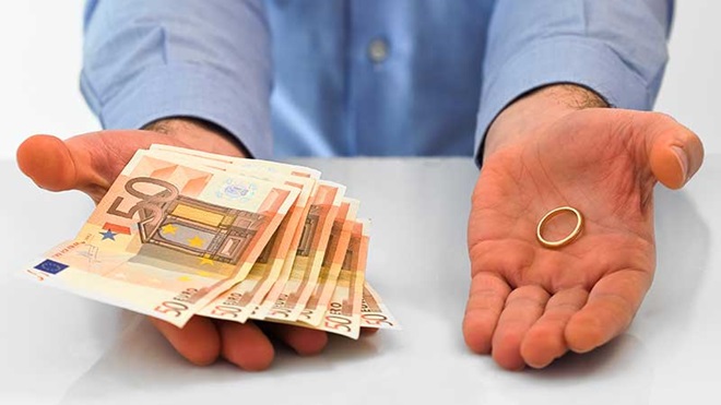 Homem com notas de 50 euros numa mão e uma aliança na outra