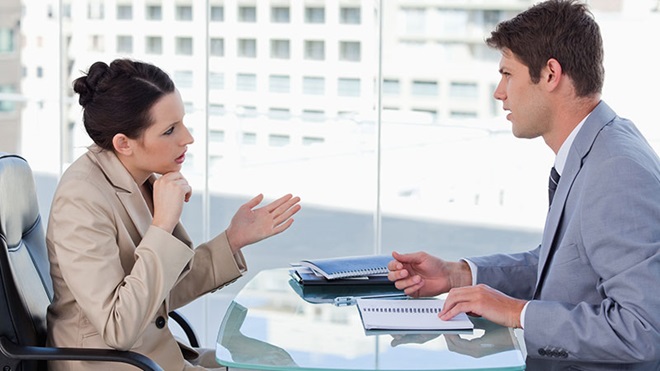 Mulher e homem a conversar sobre a rescisão do contrato de trabalho sentados no escritório
