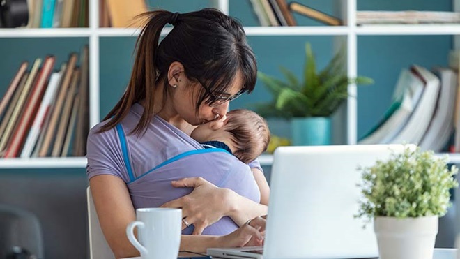 Mãe a dar um beijinho ao bebé junto a um portátil