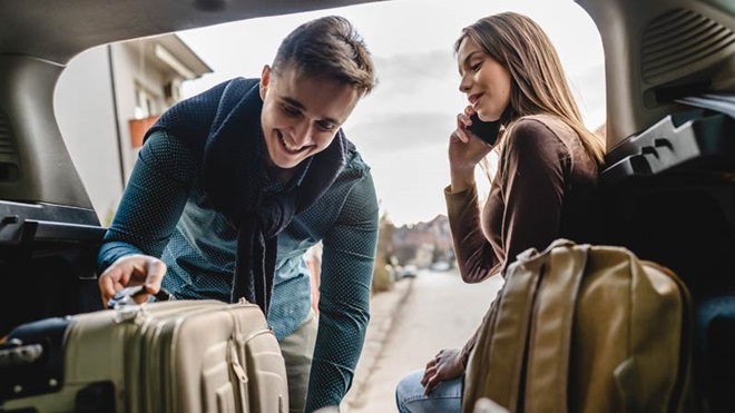 casal a colocar malas no carro